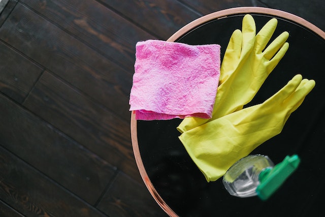 Latex gloves and a bottle of cleaning product placed on the table