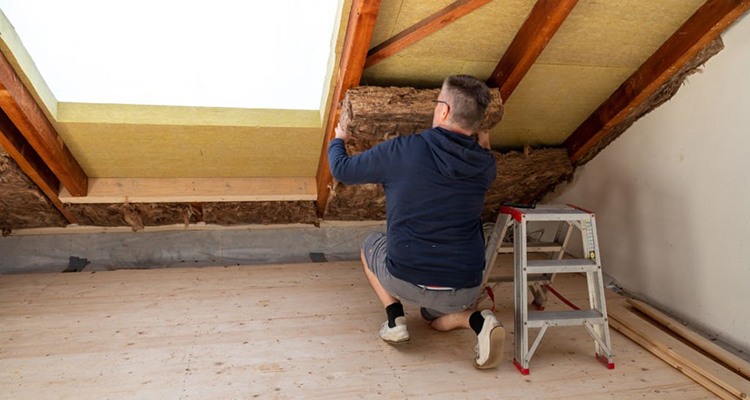 Craftsman putting insulation material to the attic.