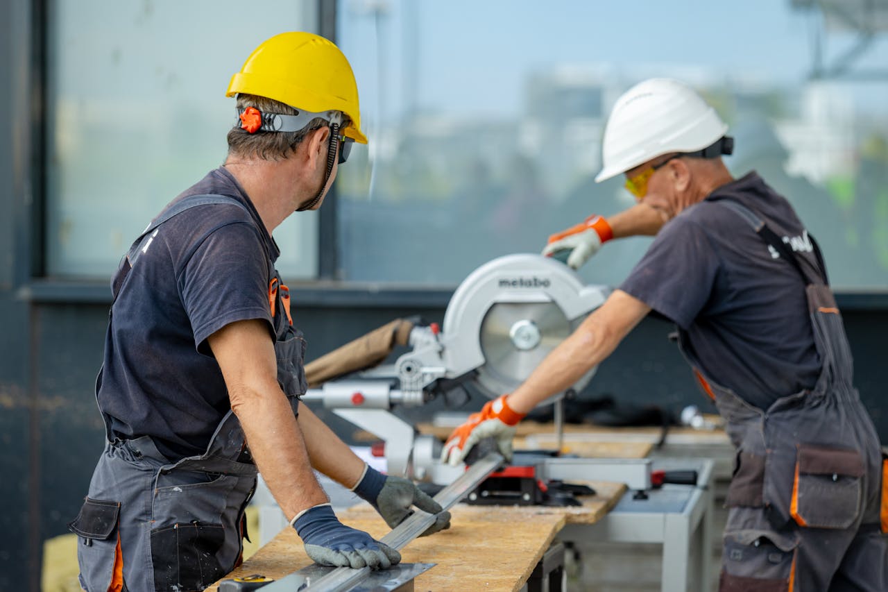 Two people cutting metal with a power saw