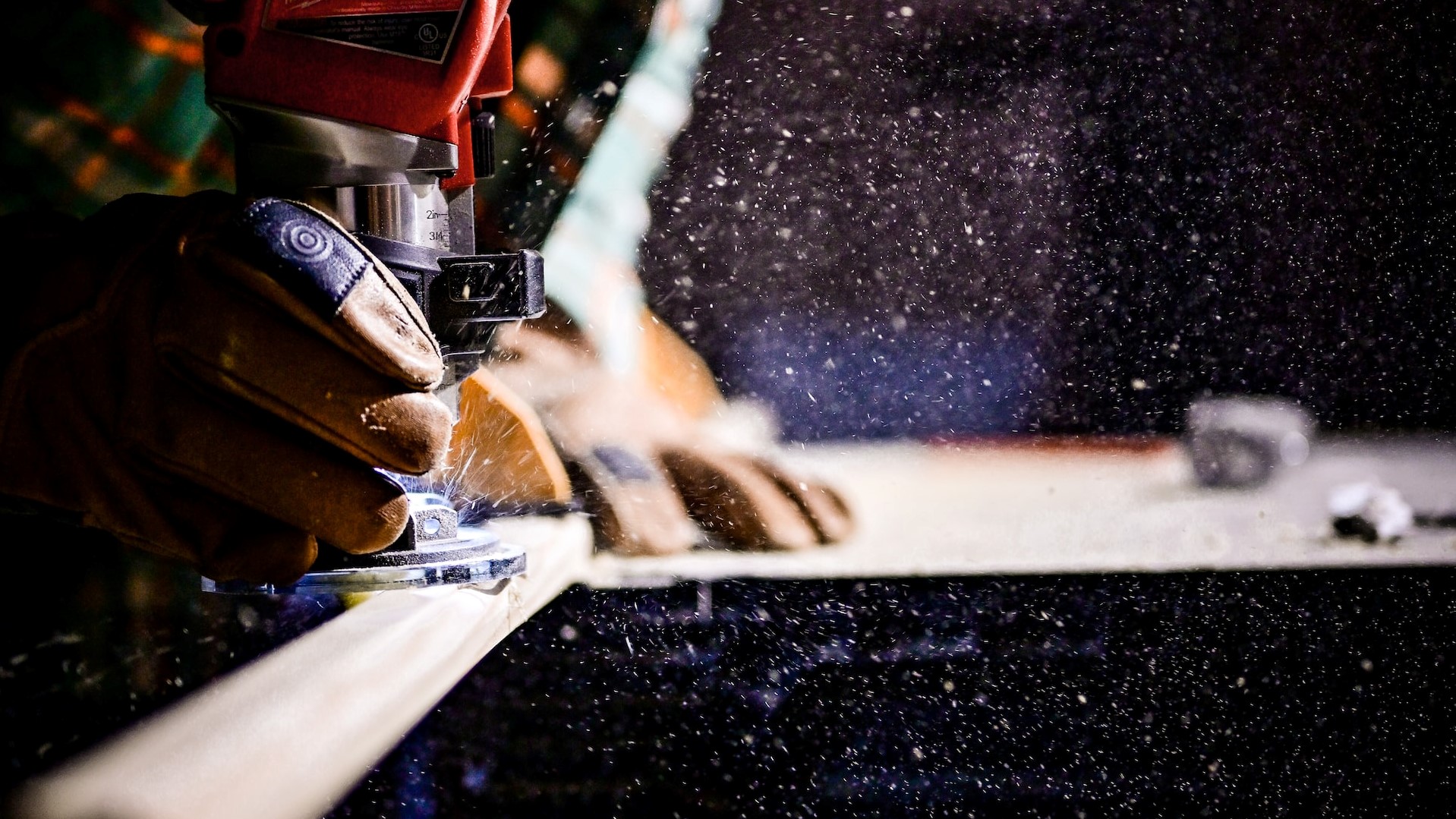 A person wearing gloves carves wood with a saw