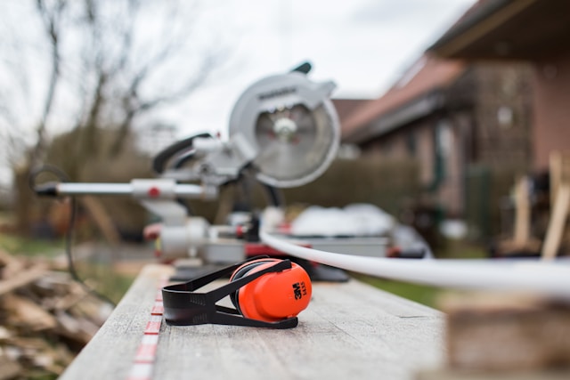 Black and red 3M earmuffs beside the miter saw